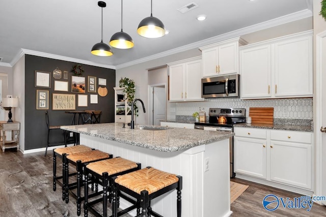 kitchen with a kitchen island with sink, light stone counters, stainless steel appliances, and white cabinets