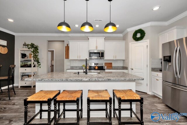 kitchen featuring appliances with stainless steel finishes, light stone countertops, a kitchen island with sink, and white cabinets