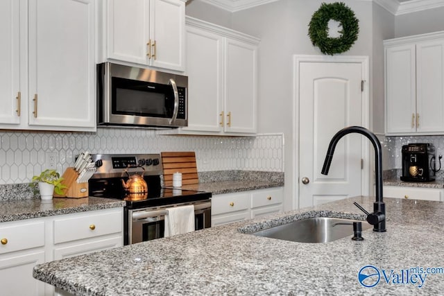 kitchen with white cabinetry, sink, light stone counters, stainless steel appliances, and crown molding