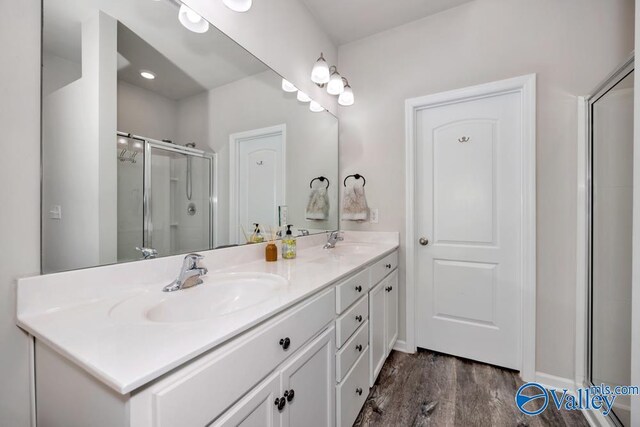 bathroom with wood-type flooring, a shower with shower door, and vanity