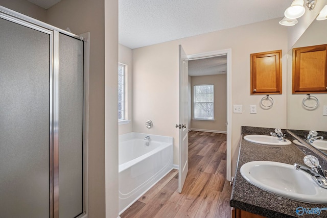 full bathroom with a sink, a textured ceiling, and wood finished floors