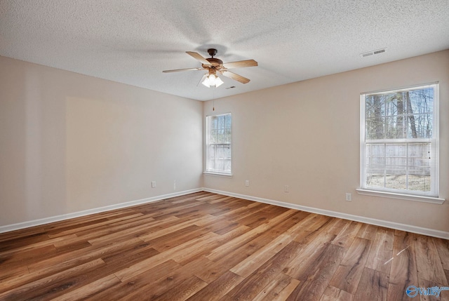 empty room featuring visible vents, baseboards, a ceiling fan, and wood finished floors