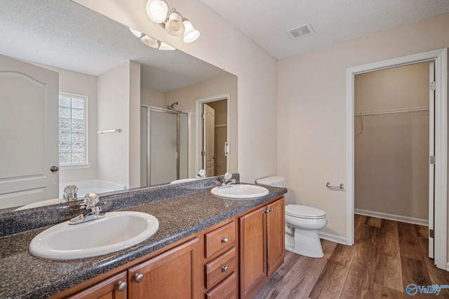 full bathroom with a sink, a stall shower, wood finished floors, and a spacious closet