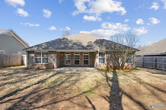 back of property with a patio area, a fenced backyard, brick siding, and roof with shingles