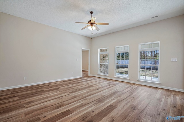 spare room with light wood-type flooring, visible vents, baseboards, and a ceiling fan