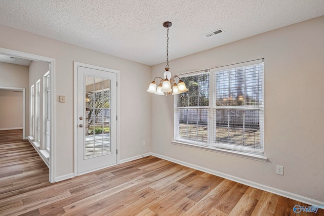 unfurnished dining area with plenty of natural light, light wood-style flooring, and visible vents