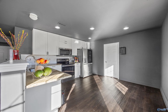 kitchen with appliances with stainless steel finishes, white cabinetry, dark hardwood / wood-style floors, light stone countertops, and decorative backsplash