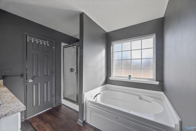 bathroom featuring vanity, hardwood / wood-style flooring, plus walk in shower, and a textured ceiling