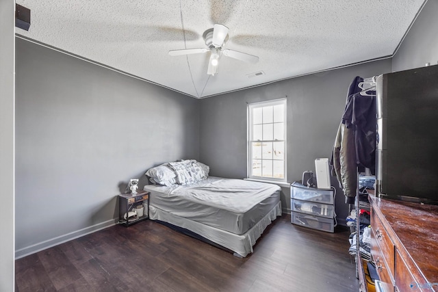 bedroom with dark hardwood / wood-style flooring, ceiling fan, and a textured ceiling