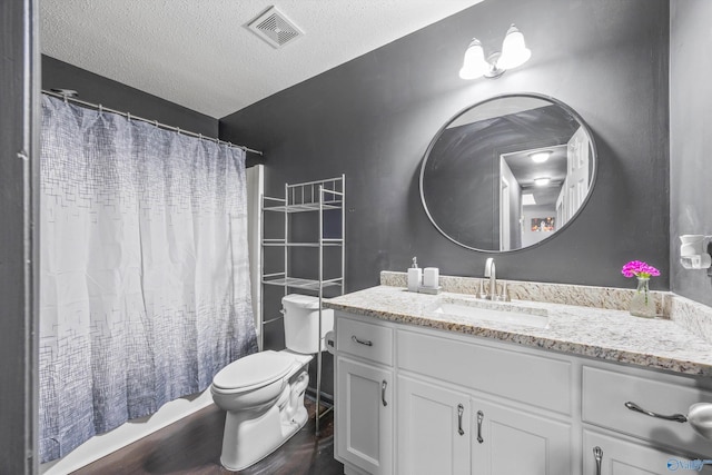 full bathroom with shower / tub combo with curtain, hardwood / wood-style flooring, vanity, toilet, and a textured ceiling