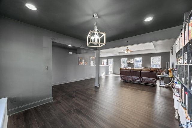 living room featuring a raised ceiling, dark wood-type flooring, and ceiling fan