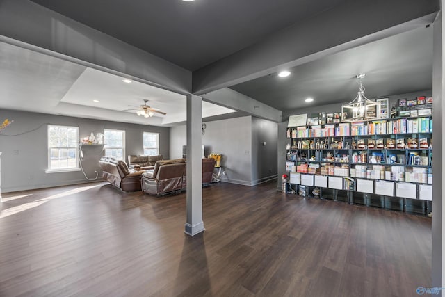 interior space featuring a raised ceiling, ceiling fan with notable chandelier, and dark hardwood / wood-style flooring