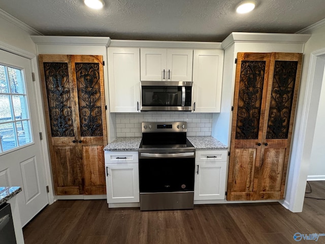 kitchen with appliances with stainless steel finishes, white cabinetry, dark wood-type flooring, and light stone counters