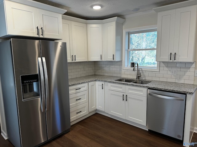 kitchen featuring light stone counters, stainless steel appliances, white cabinetry, and sink