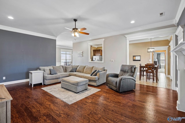 living area featuring baseboards, visible vents, a ceiling fan, ornamental molding, and dark wood-style flooring