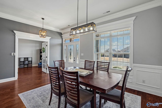 dining space with wainscoting, wood finished floors, visible vents, and crown molding