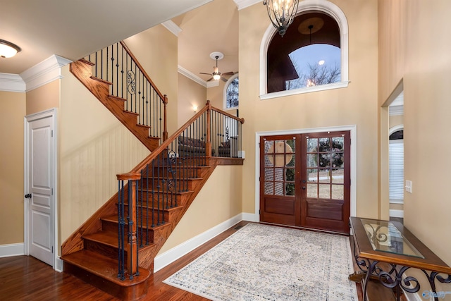 entryway featuring french doors, a high ceiling, dark hardwood / wood-style floors, crown molding, and ceiling fan with notable chandelier