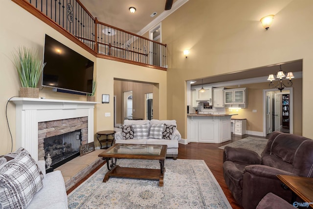 living room with hardwood / wood-style floors, a fireplace, a chandelier, and a high ceiling