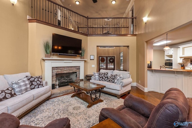 living room with sink, wood-type flooring, a fireplace, and a towering ceiling