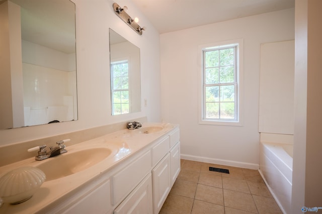 bathroom with double vanity, a bathing tub, and tile patterned floors