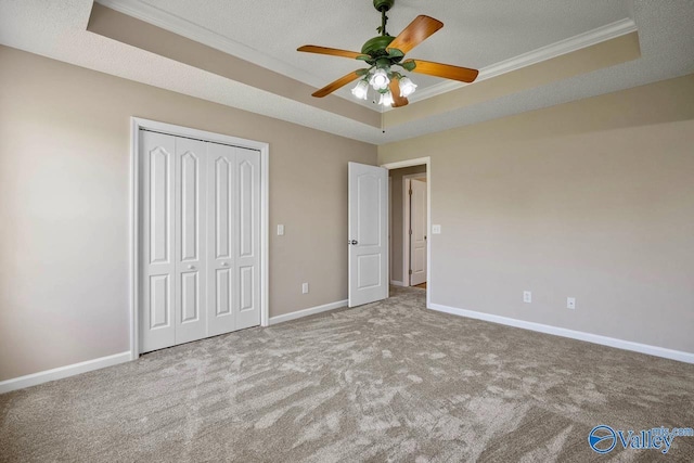 unfurnished bedroom with baseboards, carpet floors, ornamental molding, and a raised ceiling