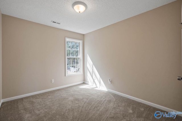 carpeted empty room featuring a textured ceiling, baseboards, and visible vents