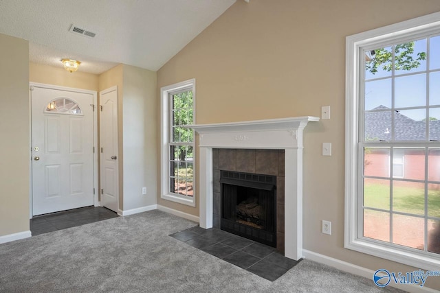 foyer featuring dark carpet, a tile fireplace, baseboards, and plenty of natural light