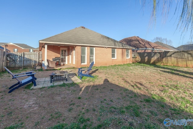 back of property featuring a yard, a patio, brick siding, and a fenced backyard