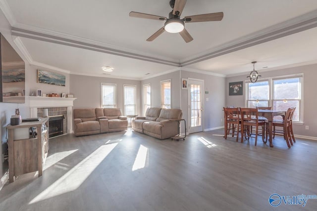 living area featuring wood finished floors, crown molding, a healthy amount of sunlight, and baseboards