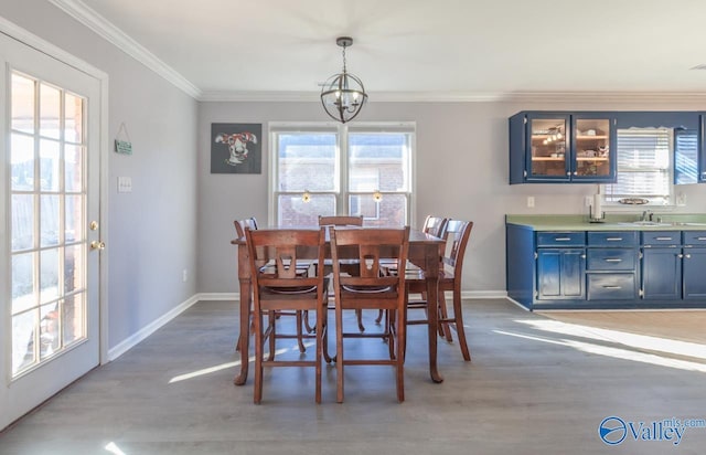 dining room featuring baseboards, light wood-style floors, a chandelier, and crown molding