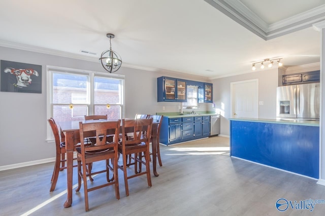 dining space featuring baseboards, visible vents, ornamental molding, light wood-style floors, and a chandelier