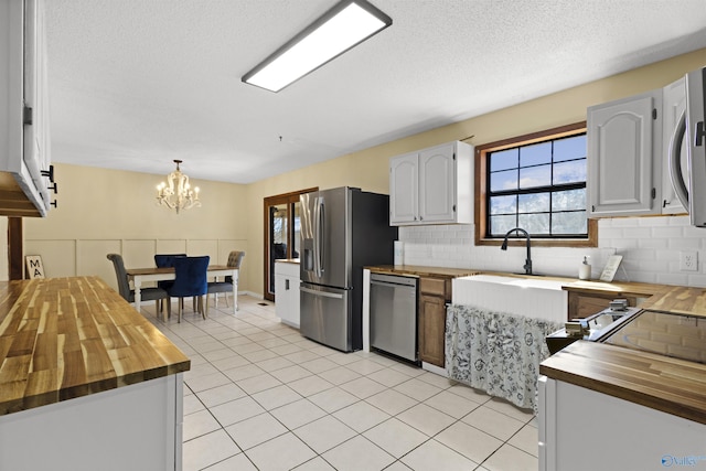 kitchen featuring stainless steel appliances, butcher block counters, white cabinetry, and light tile patterned floors