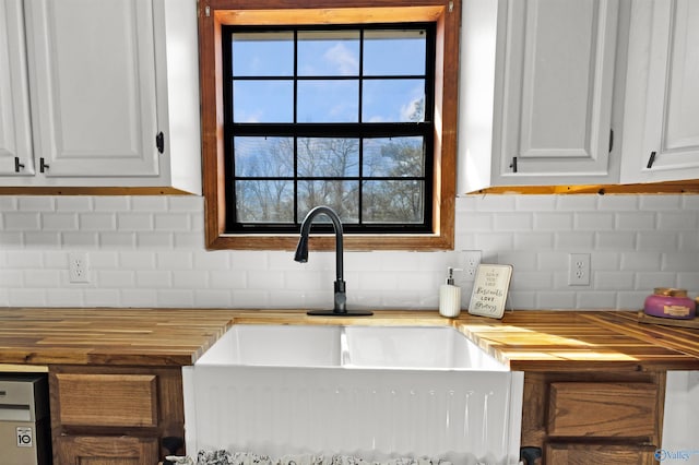 kitchen with a sink, white cabinets, wooden counters, decorative backsplash, and dishwasher