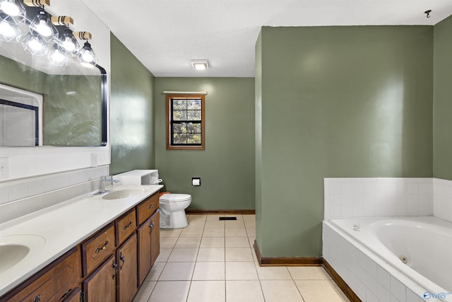 bathroom with double vanity, toilet, a sink, tile patterned flooring, and a tub with jets