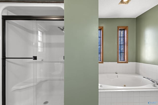 bathroom featuring a whirlpool tub, a shower stall, and a textured ceiling