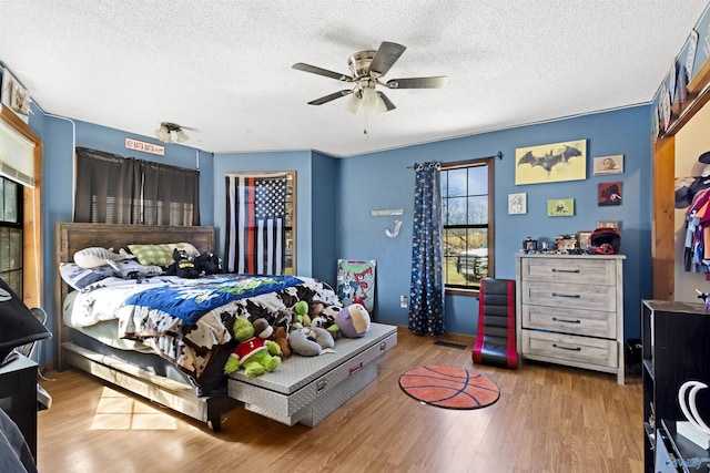 bedroom featuring ceiling fan, a textured ceiling, and wood finished floors