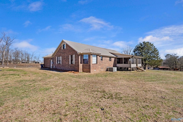 view of side of property featuring crawl space, a sunroom, a lawn, and brick siding