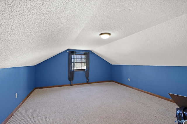 bonus room with vaulted ceiling, a textured ceiling, carpet flooring, and baseboards