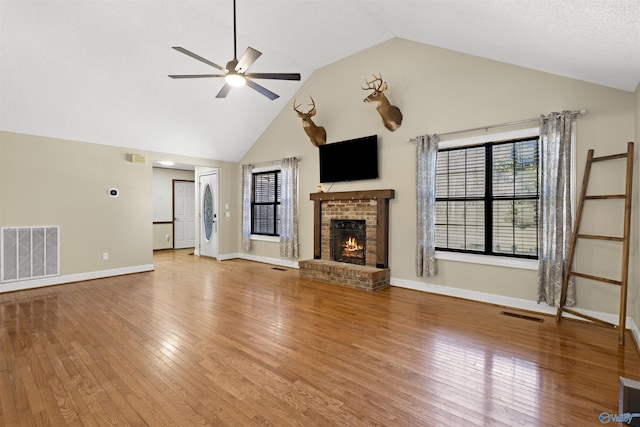 unfurnished living room with ceiling fan, a brick fireplace, wood finished floors, and visible vents