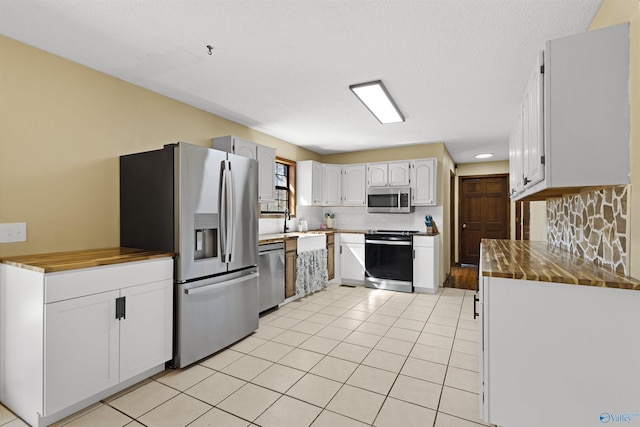 kitchen with white cabinetry, stainless steel appliances, backsplash, and light tile patterned flooring