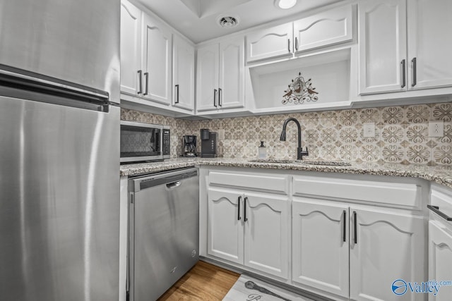 2823 Wynterhall Rd, Huntsville, AL 35803 - kitchen featuring backsplash, a sink, light stone countertops, appliances with stainless steel finishes, and white cabinetry