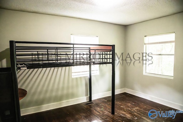525 Quincy St, Scottsboro, AL 35768 - unfurnished bedroom with hardwood / wood-style flooring, baseboards, multiple windows, and a textured ceiling