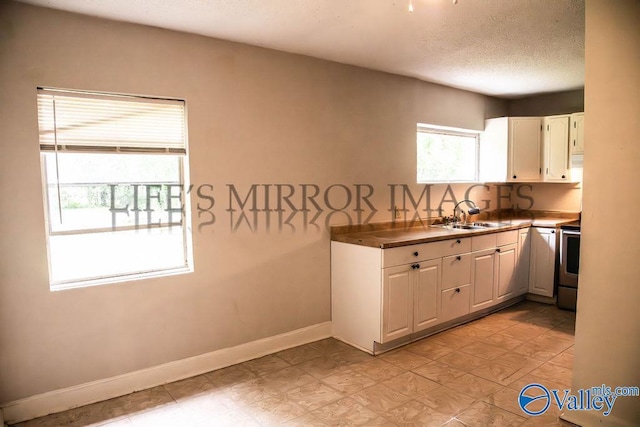 525 Quincy St, Scottsboro, AL 35768 - kitchen with stainless steel electric stove, white cabinetry, a sink, baseboards, and a textured ceiling