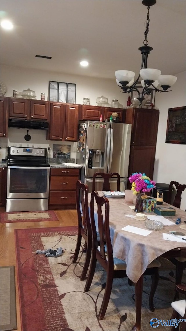 kitchen featuring a notable chandelier, decorative light fixtures, stainless steel appliances, and light hardwood / wood-style floors