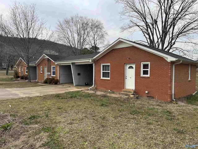 view of front of house with brick siding, entry steps, concrete driveway, a front yard, and a carport