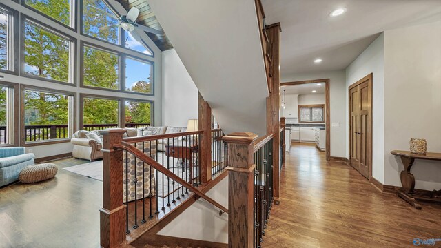 stairway featuring a healthy amount of sunlight, high vaulted ceiling, ceiling fan, and hardwood / wood-style floors