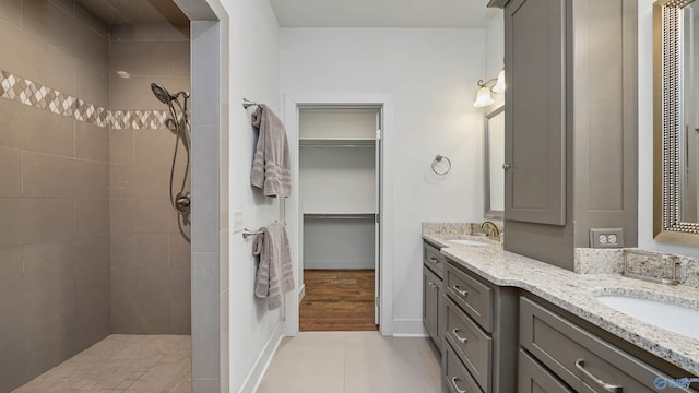 bathroom with double vanity, wood-type flooring, and tiled shower