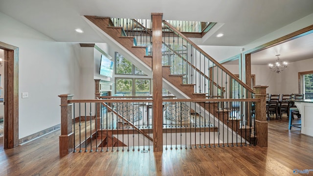 staircase featuring wood-type flooring and a chandelier