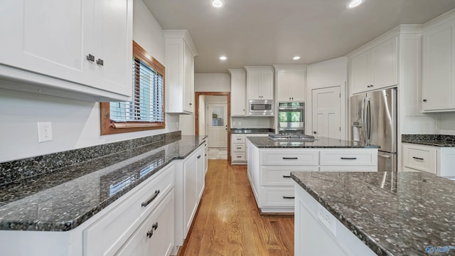 kitchen featuring appliances with stainless steel finishes, white cabinetry, a healthy amount of sunlight, and light wood-type flooring