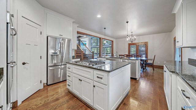 kitchen with dark stone counters, light hardwood / wood-style flooring, appliances with stainless steel finishes, and a kitchen island